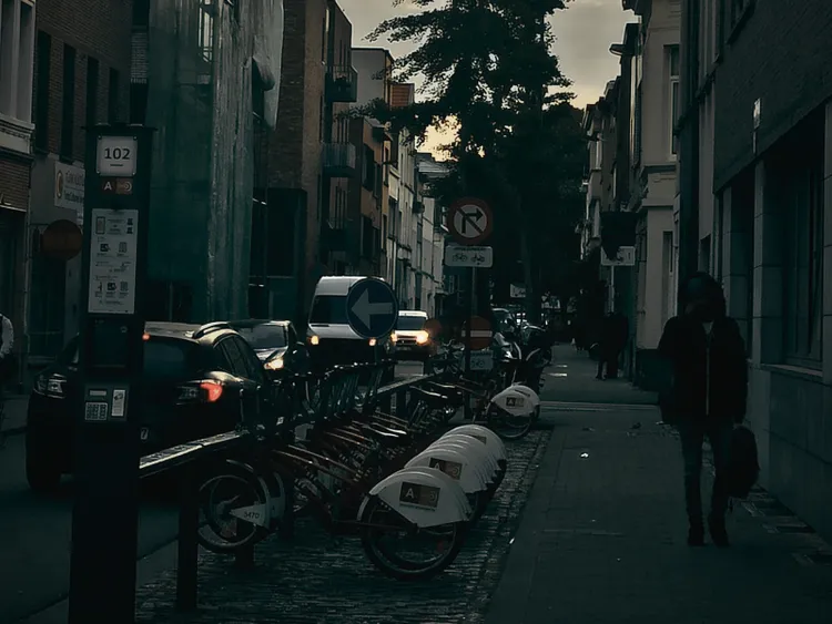 A street in Antwerp, Belgium. There is a person walking and a row of bicycles chained to a rack.